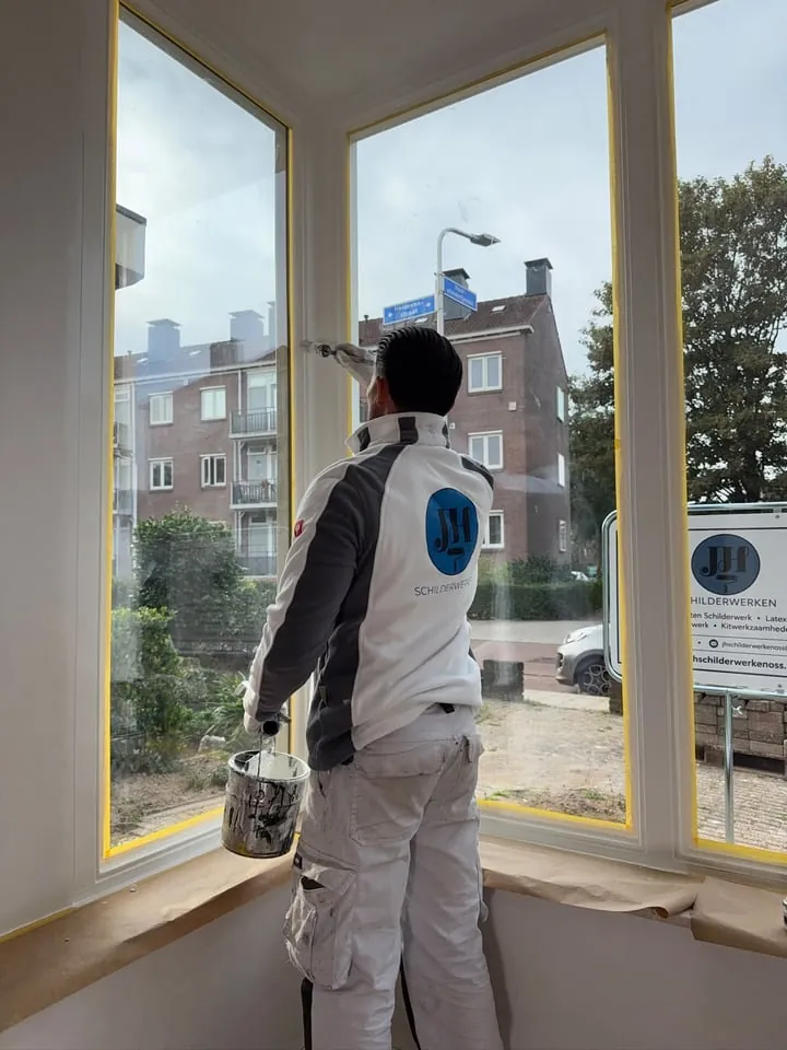 Justin lakt een raamkozijn af in een erker