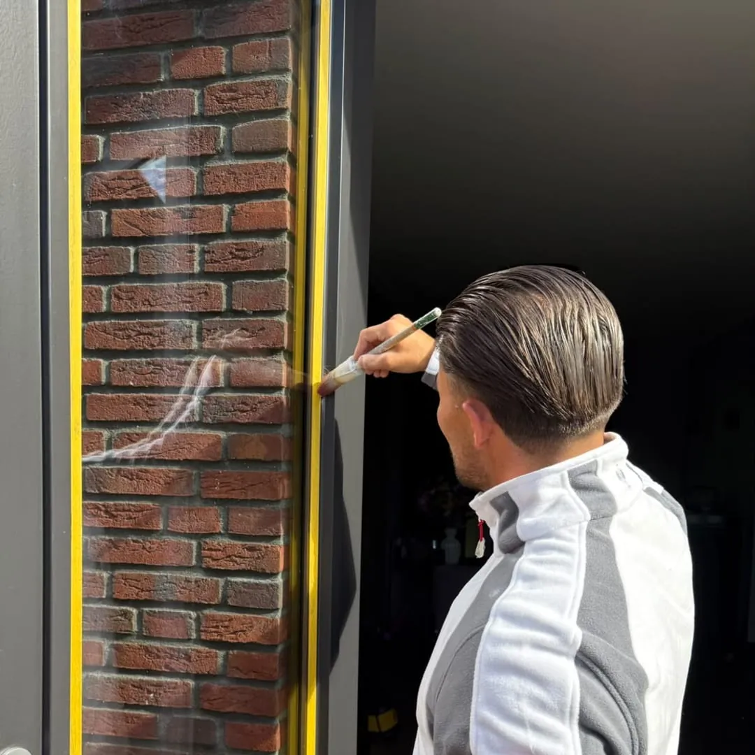Schilder werkt een houten kozijn af met een kwast