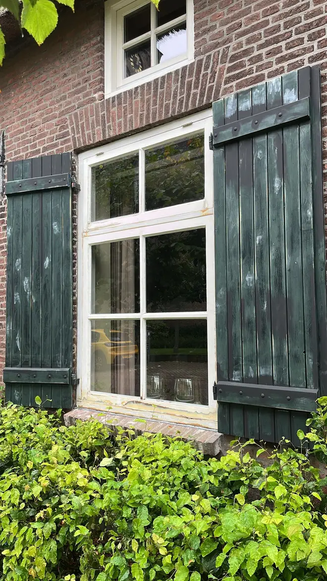 Boerderijraam met doffe luiken en plamuurplekken, voor het schilderen