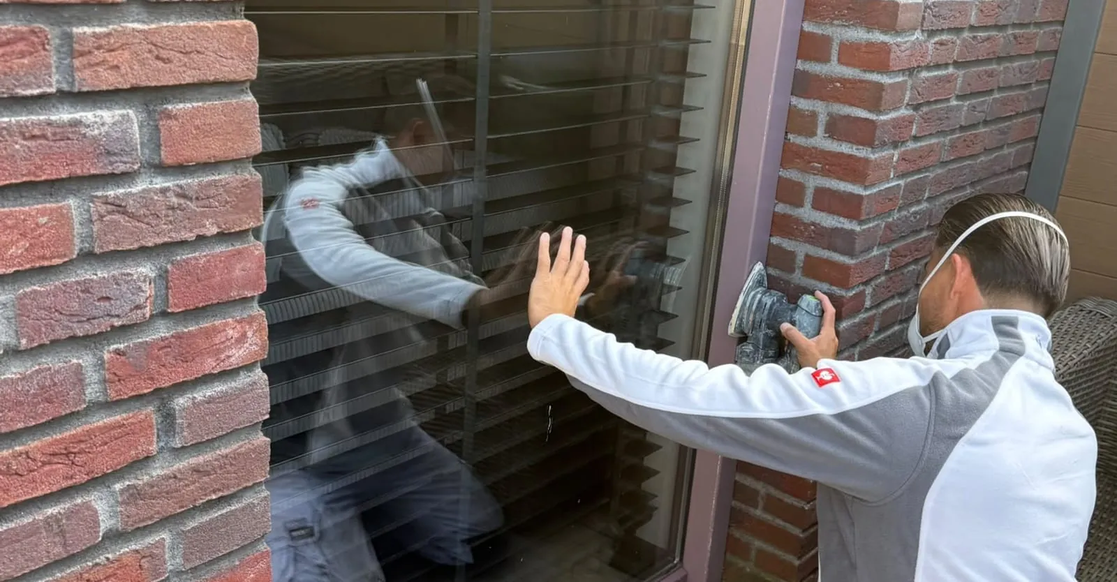 Justin schuurt een kozijn machinaal op bij een woning in Oss