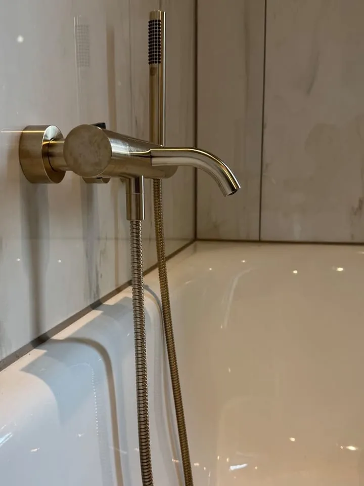 Nieuwe sanitairkit langs de aansluiting van tegelwerk en douchebak
