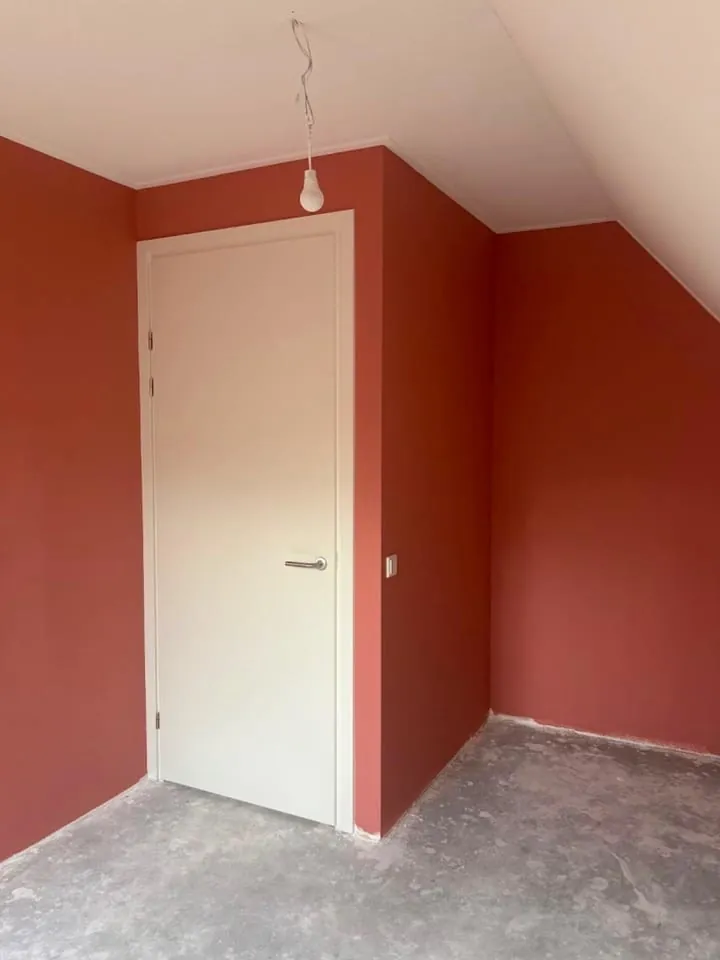 Slaapkamer in terracotta met wit gelakte deur en kozijn