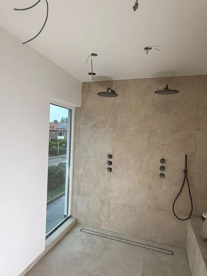 Geschilderd plafond boven het tegelwerk van een inloopdouche