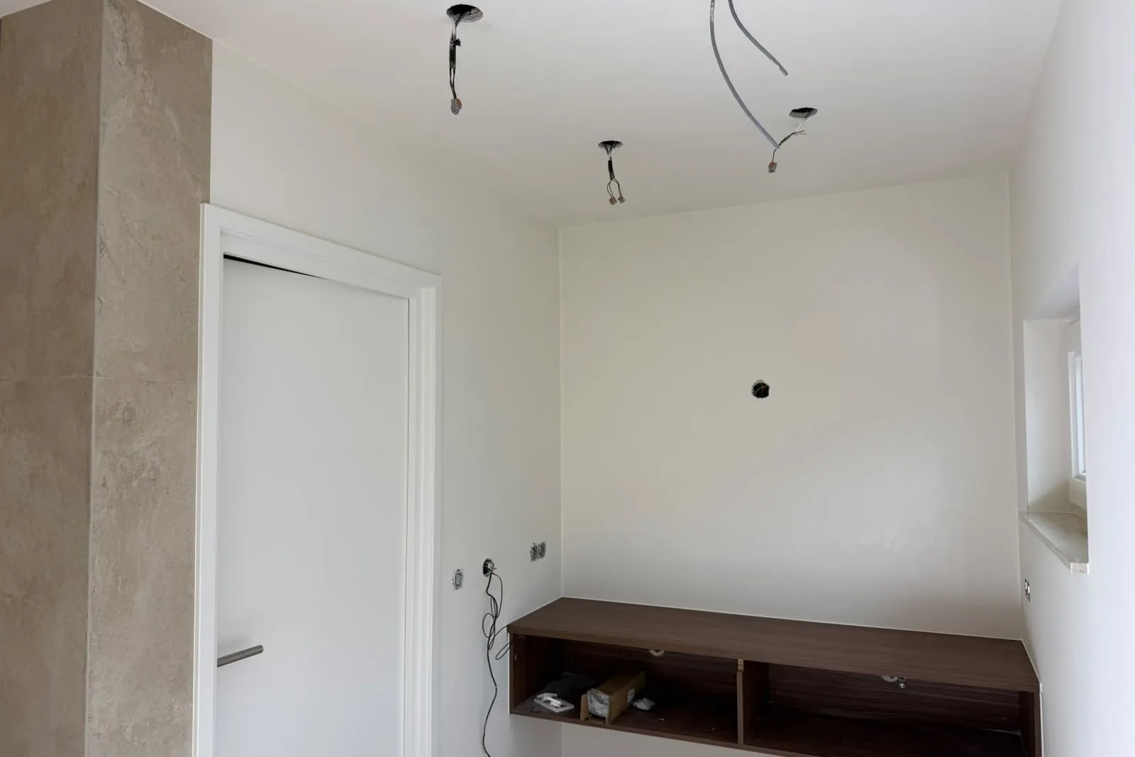 Geschilderd plafond en wanden rond een deurkozijn, naast een tegelwand en een houten wandmeubel